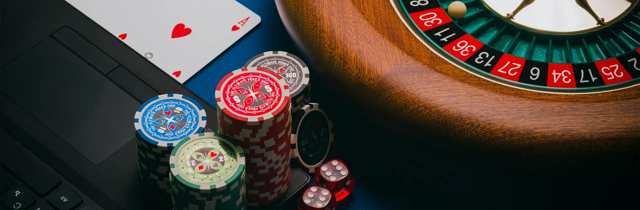 Rueda de ruleta, fichas, naipes y dados sobre un paño verde oscuro